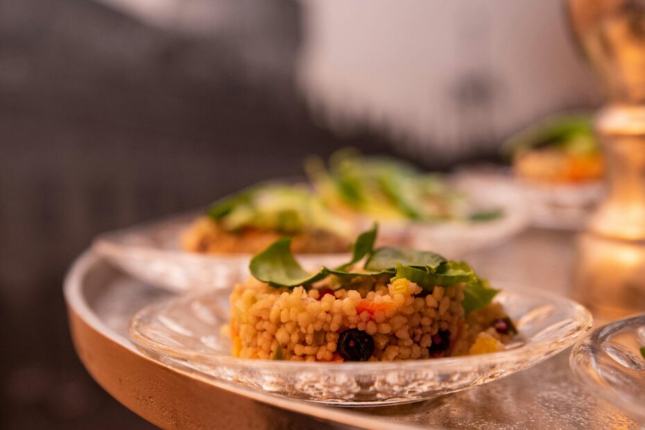 Delicious fregola pasta on a clear glass plate, garnished with greens.